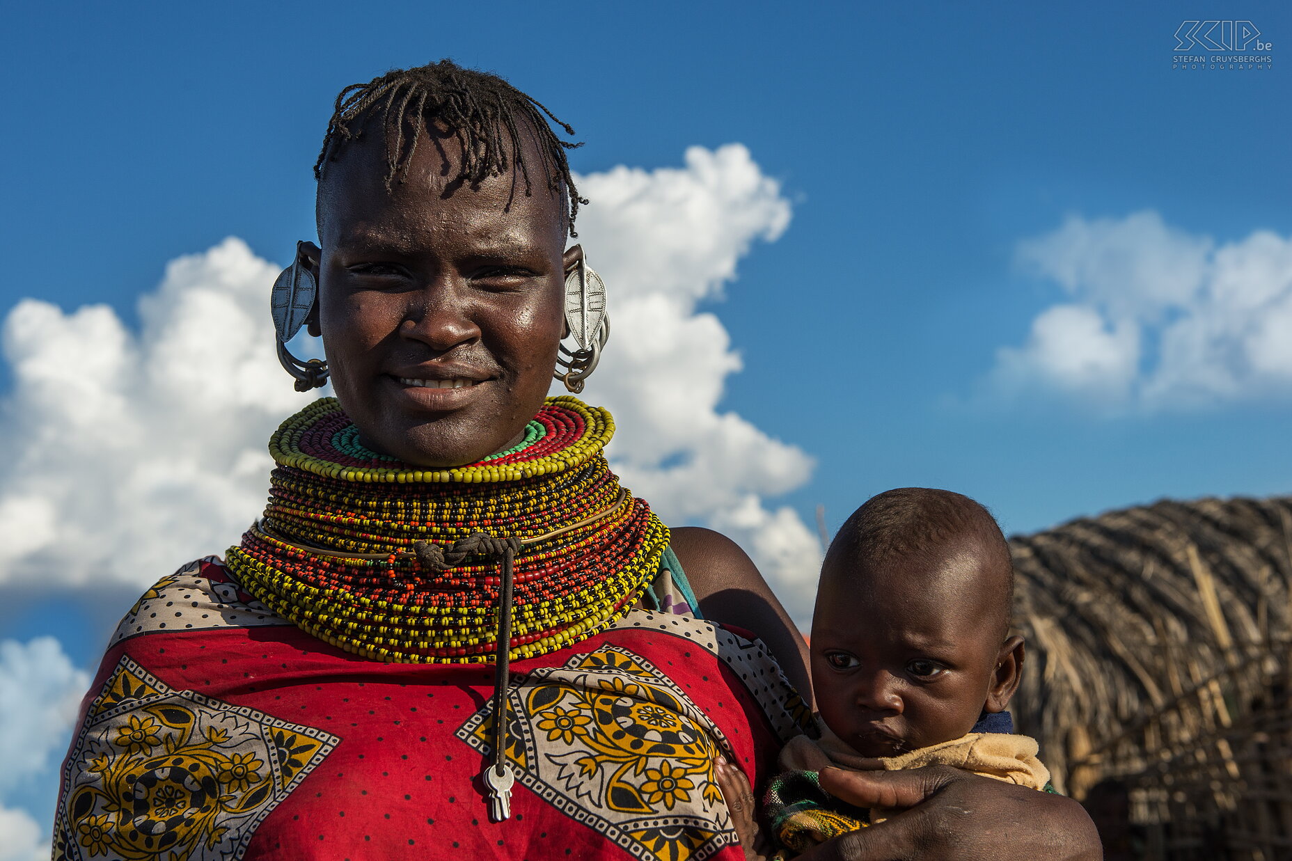 Lake Turkana - Turkana vrouw met baby De Turkana is een grote stam die nog vrij traditioneel leeft. Het zijn voornamelijk semi-nomadische veehouders. Vrouwen hebben vaak een Mohawk haarstijl en ze dragen vele kleurrijke halskettingen en armbanden van kralen. Getrouwde vrouwen zijn vaak te herkennen aan de aluminium oorringen in de vorm van een blad. Soms dragen ze ook nog kleding van geiten en koeien leer.  Stefan Cruysberghs